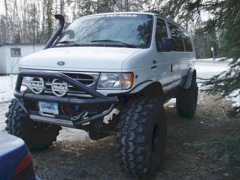 2000 Ford E350 - This heavily modified Ford E-Series van features extreme off-road tires and a snorkel, indicating a model year prior to 2000 based on its b…