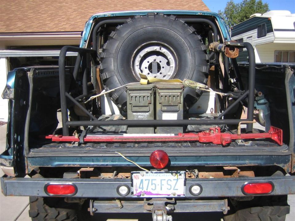Rear view of a 1994 Ford Bronco with a spare tire, ammo cans, and a jack in the bed