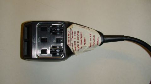 1979 Ford Bronco - A Ford CB radio microphone is shown with its control buttons and a warning label attached.