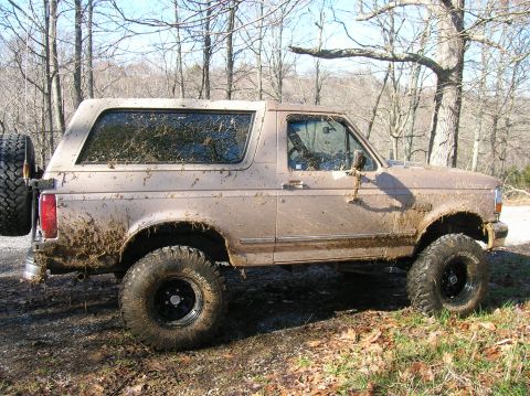 1996 Ford Bronco - This 1996 Ford Bronco is heavily covered in mud, suggesting off-road use.