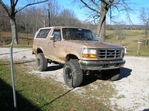 1996 Ford Bronco - This mud-splattered Ford Bronco is ready for off-road adventures, parked outside on a sunny day.