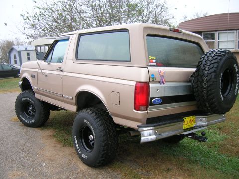 1996 Ford Bronco - This lifted Ford Bronco is parked on a gravel driveway with grass and houses in the background.