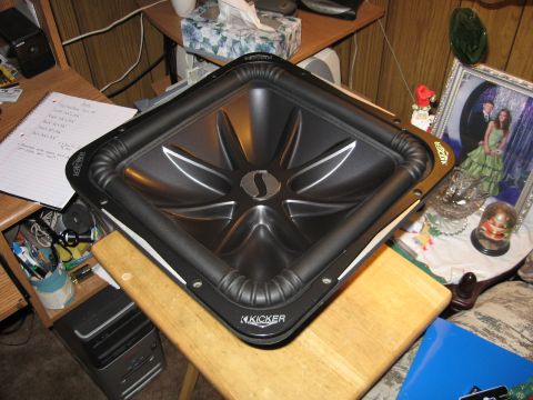 1992 Ford Crown Victoria - A Kicker subwoofer is shown on a wooden surface, with a notebook and computer tower nearby.