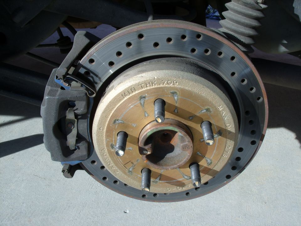 Cross-drilled brake rotor with exposed lug studs and floating caliper