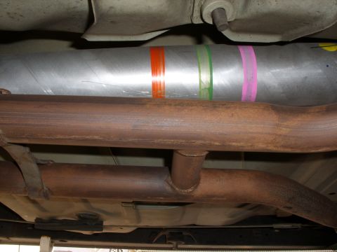 2005 Ford Crown Victoria - The driveshaft and exhaust system of a vehicle are shown from below, with colorful tape bands on the driveshaft.