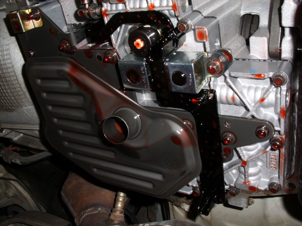 Automatic transmission with pan off showing the fluid filter and red ATF on the valve body