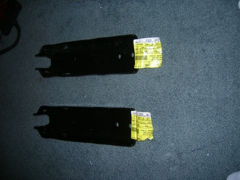 1979 Ford Bronco - Two automotive suspension parts with labels are shown on a carpeted floor.