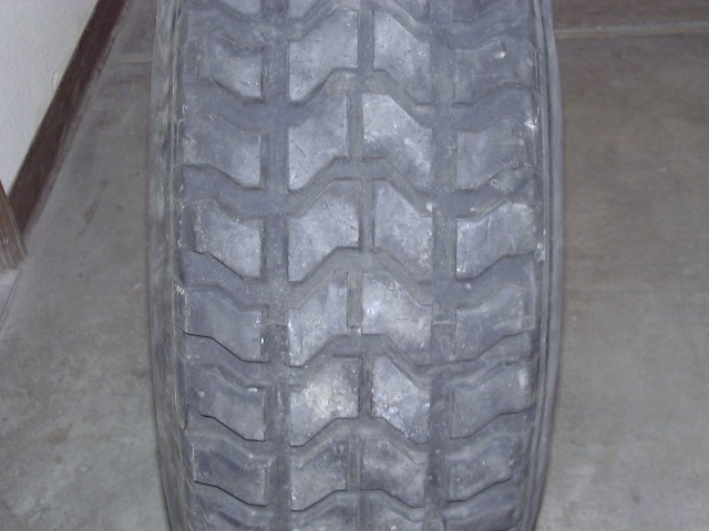 Close-up of worn all-terrain tire tread on a tire standing on concrete indoors