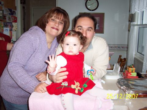 2000 Ford Crown Victoria - A family celebrates the holidays, posing for a picture with a baby dressed in a red outfit.