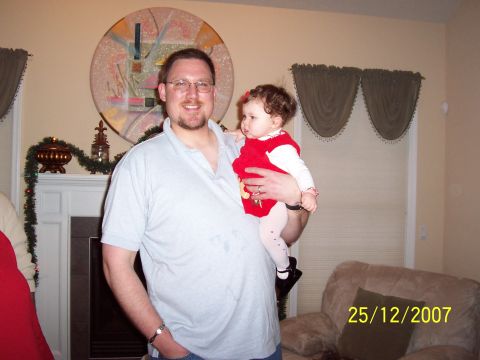 2000 Ford Crown Victoria - A man holds a baby in front of a fireplace decorated for Christmas.