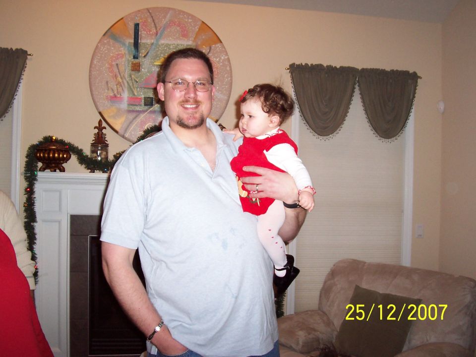 Man holding a baby in a living room with Christmas decorations