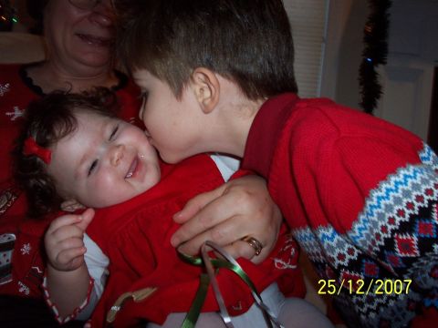 2000 Ford Crown Victoria - A young boy kisses his baby sister on the cheek, with a Christmas tree and date 25/12/2007 visible in the background.