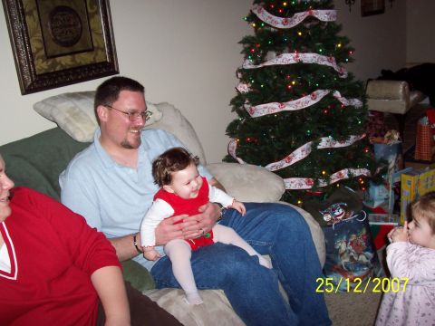 2000 Ford Crown Victoria - A family celebrates Christmas together, with a decorated tree and gifts visible in the background.