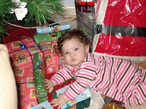 2000 Ford Crown Victoria - A baby lies amongst Christmas presents under a tree, looking towards the camera.