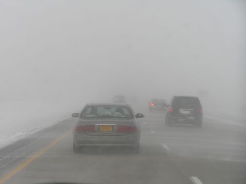 2000 Ford Excursion - Visibility is extremely low due to heavy fog on the highway, making driving hazardous.