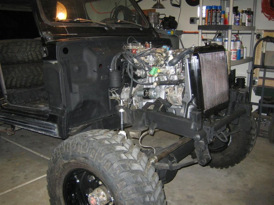 Black 1987 Suzuki Samurai with engine removed, front view, in a garage