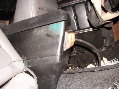 1973 Ford Ranchero - Interior view of a black plastic center console with green paint scuffs mounted beside a gray upholstered seat, with an amber lamp lens set…
