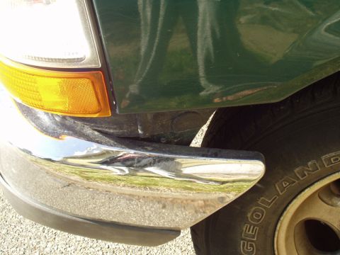 1999 Ford Ranger - Detail of the front corner of a green truck, including the headlight and bumper assembly.