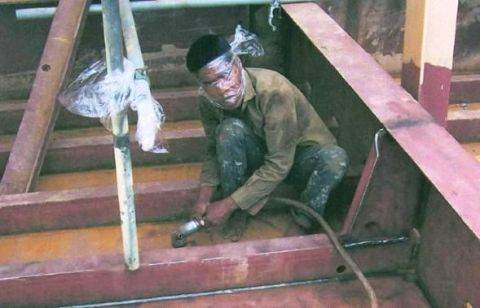 1989 Ford Bronco - A construction worker grinds metal beams while wearing plastic wrap over his face for protection.