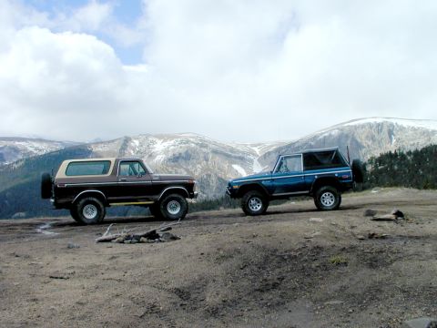 1979 Ford Bronco - Two classic Ford Broncos are parked on a scenic mountain overlook under a cloudy sky.