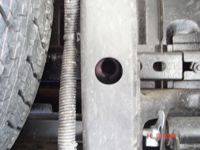 Close-up of vehicle frame and tire with corrugated hose