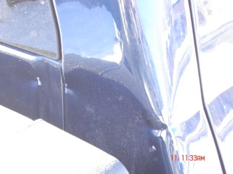 1981 Ford Bronco - Close-up of a damaged dark blue vehicle body panel with a visible watermark.