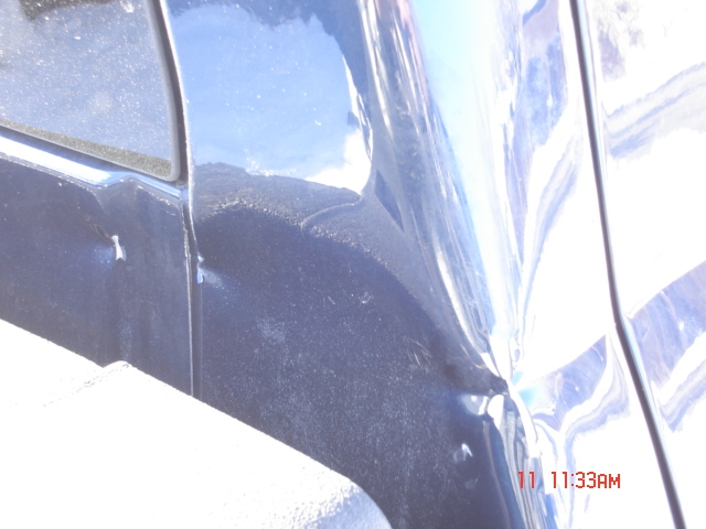 Dark blue vehicle body panel showing dents and scratches. Watermark reads SUPERMOTORS.NET