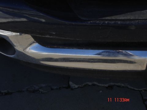 1981 Ford Bronco - A close-up view of a vehicle's rear bumper and exhaust pipe, with a landscape reflected on the chrome.
