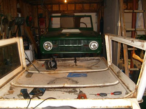1974 Ford Bronco - 1974 Ford Bronco front clip and disassembled doors in a garage setting.