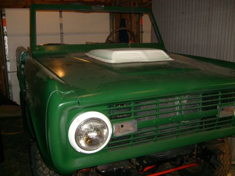 1974 Ford Bronco - Front view of a green 1974 Ford Bronco, a prominent hood scoop and horizontal grille.