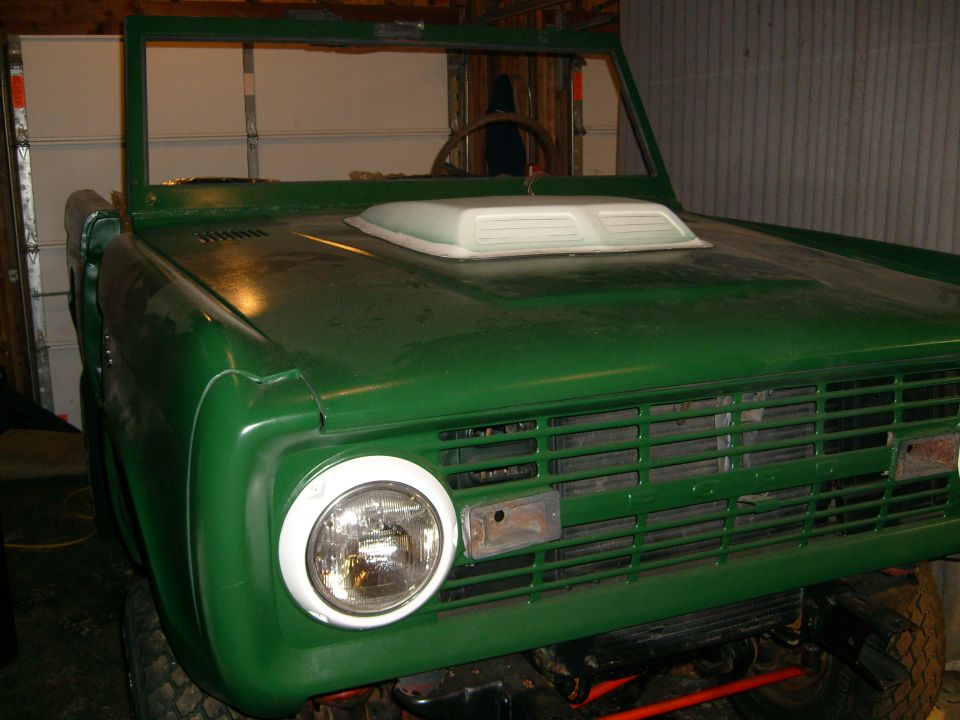 Green 1974 Ford Bronco front end with hood scoop and round headlights