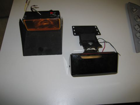 2001 Ford Crown Victoria - Two separate vehicle lighting components are shown on a white surface, one with an amber lens and the other with a red lens.