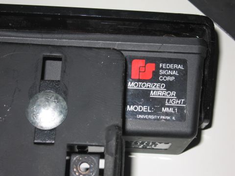 2001 Ford Crown Victoria - Close-up of a Federal Signal Corp. motorized mirror light, model MML1, with visible text and mounting hardware.