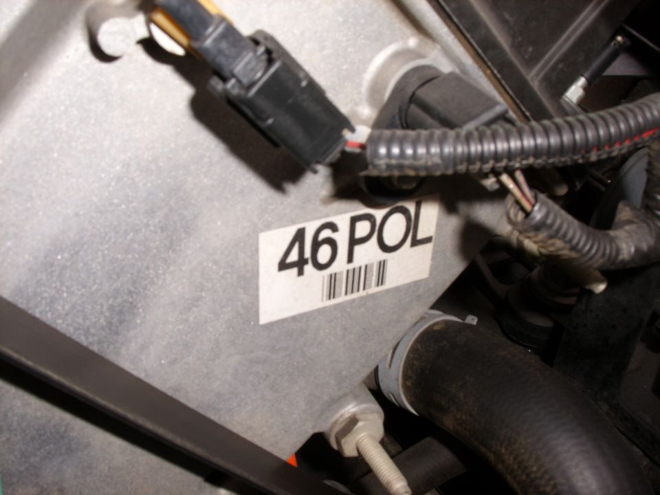 Engine bay connector and wiring with '46 POL' barcode label on gray metal