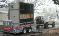 1996 Ford Bronco - A lifted Ford Bronco is seen from the rear, towing a large, multi-sectioned structure on a U-Haul trailer through muddy terrain.
