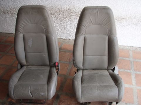 1995 Ford F-150 - A pair of gray leather car seats are shown, with one seat exhibiting wear and tear.