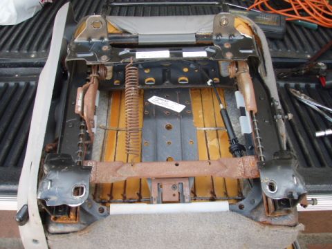 1995 Ford F-150 - The underside of a vehicle seat, showing its internal frame and suspension system, is displayed in a truck bed.