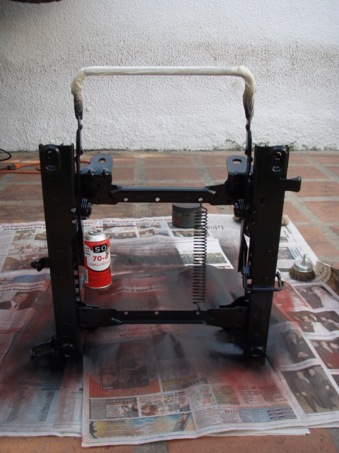 1995 Ford F-150 - A black metal seat frame is shown from the front, resting on a layer of newspapers.