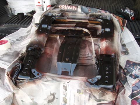 1995 Ford F-150 - A car part is being spray painted black, laid out on newspaper in the bed of a truck.