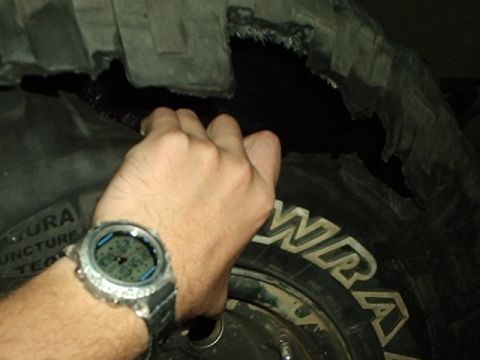 1995 Ford F-150 - A hand wearing a chunky digital watch reaches into a large torn hole ripped through the tread and shoulder of a Goodyear Wrangler off-road…