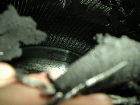1995 Ford F-150 - Close-up view of damaged tire tread and debris within a wheel well.