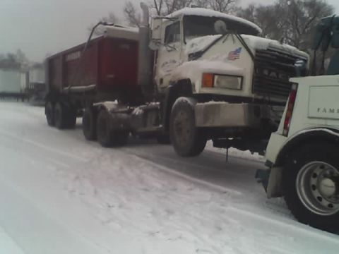 1992 Ford Bronco - A Mack truck and trailer are being towed by a tow truck in snowy conditions.