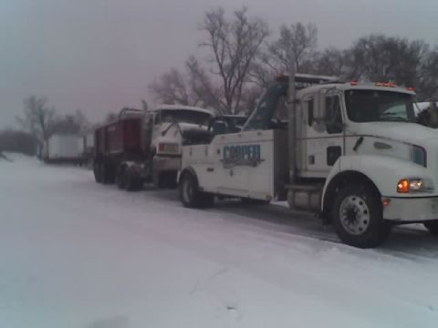1992 Ford Bronco - A tow truck is preparing to tow a dump truck on a snowy day.