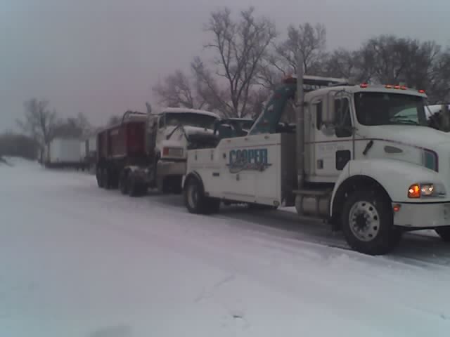 tow truck hooking up to a dump truck in the snow
