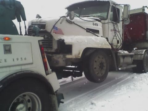 1992 Ford Bronco - A tow truck is seen assisting a semi-truck on a snow-covered road.