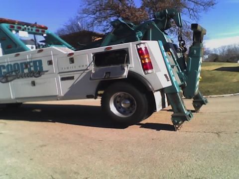 1992 Ford Bronco - Tow truck with "COOPER Sculls FAMILY OWN" text on its side.