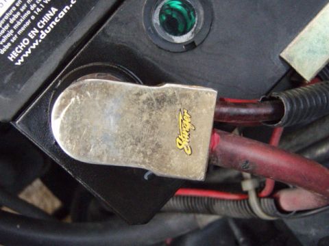 1995 Ford F-150 - A close-up view of a car battery terminal, showing red cables and a black casing with a 'Stinger' logo.
