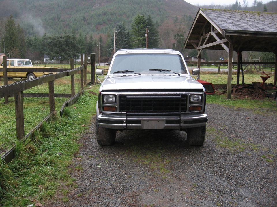 White 1980s Ford Bronco front view parked on gravel driveway in rural setting