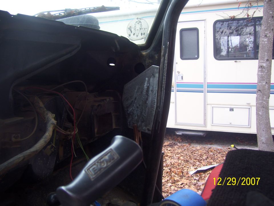 Vehicle interior showing exposed wiring and dashboard components. RV visible in background