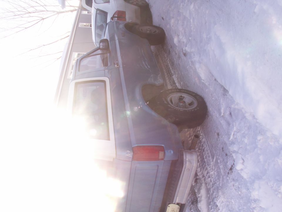 1995 Ford Bronco parked in snow next to a white vehicle